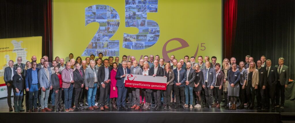 e5-Gemeindevertreter:innen stehen auf der Bühne im Kongress St. Johann und halten gemeinsam mit Landesrat Schwaiger ein e5-Schild