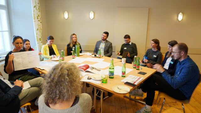 Workshop, Personen sitzen um einen Tisch und besprechen