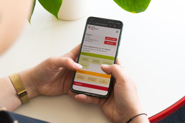 Person hält ein Smartphone auf dem der Heizungscheck zu sehen ist