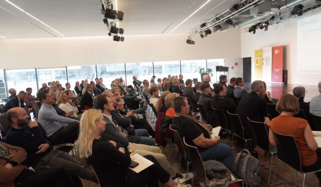 Publikum vor einer Bühne mit Vortrag des SIR