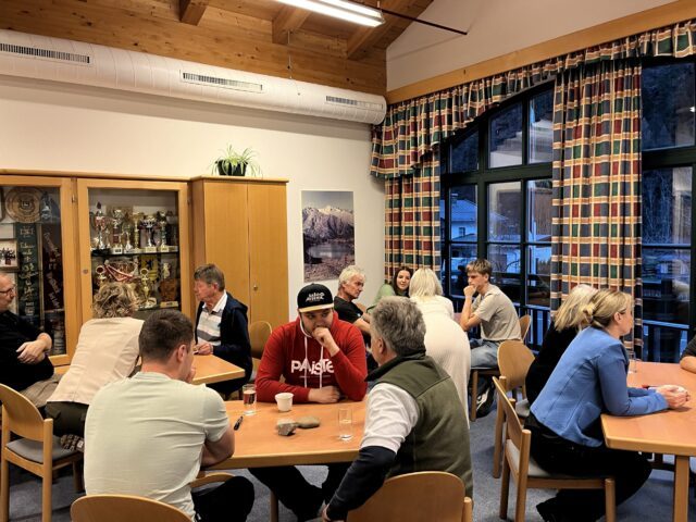 Weißbacher Bürgerinnen und Bürger sitzen in Kleingruppen an Tischen beieinander und sind im Gespräch.