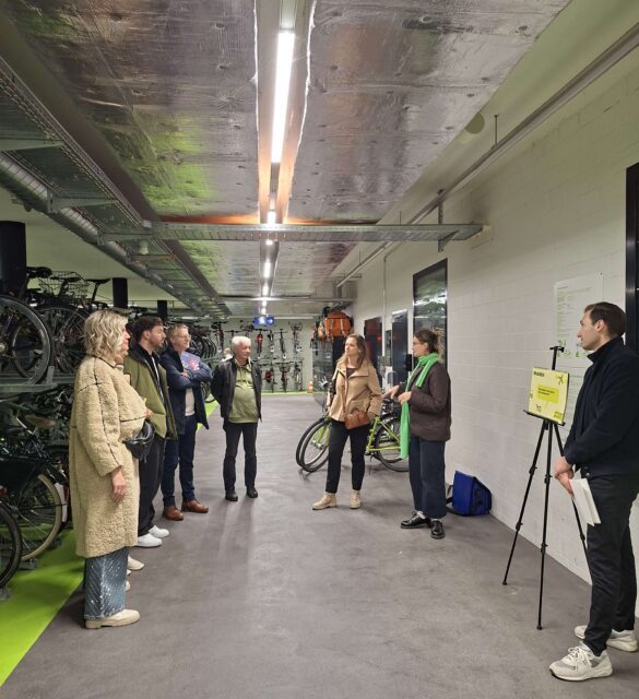 Eine Gruppe von Menschen steht in einer Radgarage und hört einer Referentin zu
