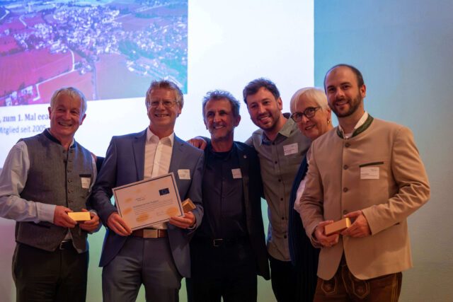 Fünf Männer und eine Frau halten Urkunden und Preise in den Händen