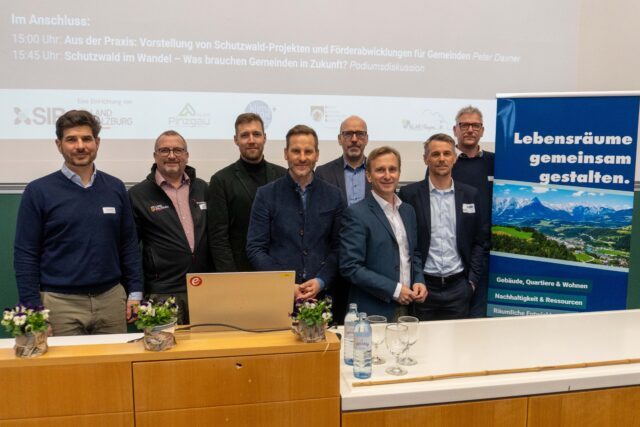 8 Personen, die Organisatoren und Vortragenden der Naturgefahrentagung, stehen neben einem SIR-Rollup auf dem steht