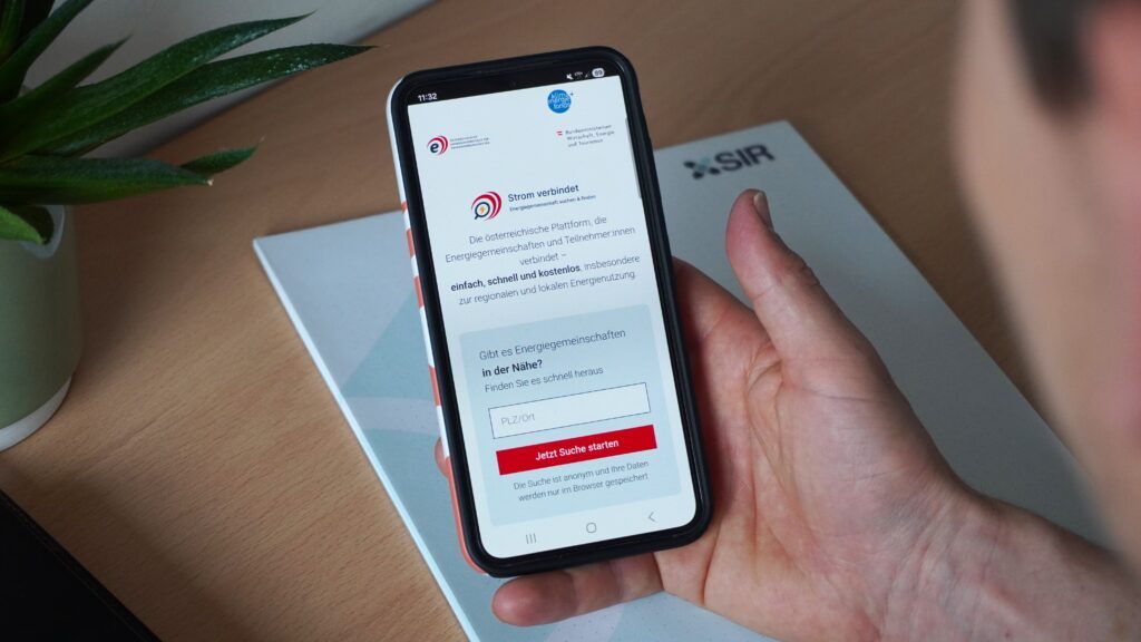 Eine Hand hält ein Smartphone auf dem die Plattform