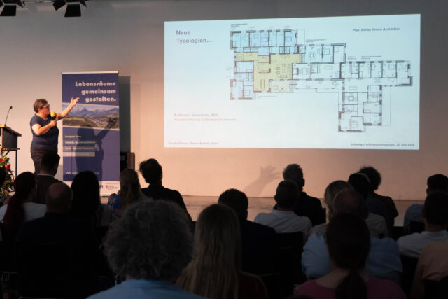 Claudia Thiesen zeigt auf einer Powerpoint-Folie den Grundriss einer Clusterwohnung.