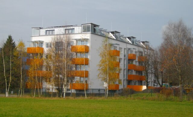 Ein weißes Wohnhaus mit orangenen Balkonen